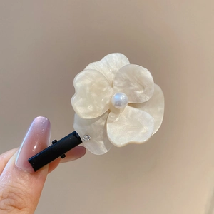 Détail de la pince à cheveux fleur avec centre perlé et strass sur pétales en nacre blanche
