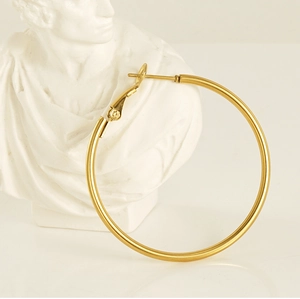 Artistic display of large 18K gold-plated stainless steel hoop earring on a white statue