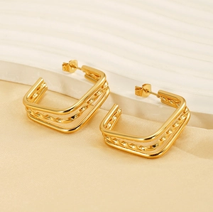 Macro shot of gold-plated titanium steel layered U-shape earrings on cream satin
