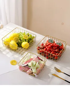 Three gold metal mesh fruit baskets filled with fresh lemons and snacks on marble table