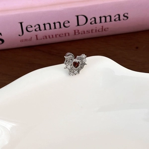 Detail of silver spider web stud earring with red heart zircon and white stones