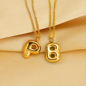 Collana con ciondolo a bolla con lettere P e B dorate su sfondo di seta