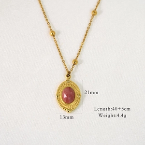 Detailed view of oval gold pendant with pink gemstone and size specification labels