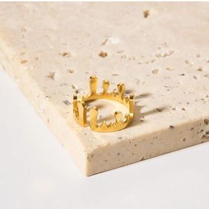 Macro shot of gold lava crown drip ring displayed on a natural beige stone pedestal