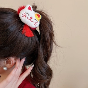 Detail of plush cat hair tie with red tassel accessory on a ponytail hairstyle