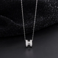 Macro detail of silver S925 H-shaped pendant with sparkling zircon micro-paving
