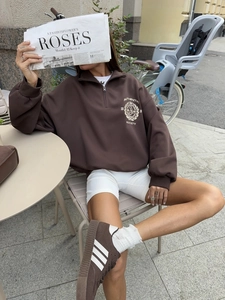 Detail of vintage dark brown half-zip sweatshirt with chest logo in street scene