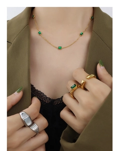 Detail of emerald green zircon necklace with gold plated chain on model in green suit