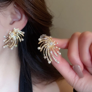 Detail of starburst earring with gold metal, sparkling rhinestones and white pearls