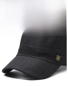 Detail of a charcoal flat top military cap with a square metal logo and stiff curved brim