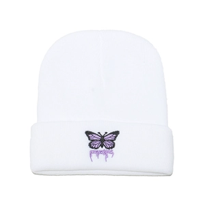 Gros plan du bonnet en tricot blanc avec broderie papillon violette et lettrage d'art