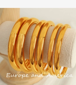 Polished 18K gold-plated minimalist bangle bracelets in various thickness on a velvet stand