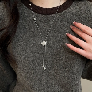 Vue détaillée du long collier en Y argenté avec perles et zircons sur un pull gris foncé