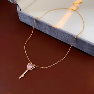 Golden key necklace with pink heart zircon pendant on premium leather background