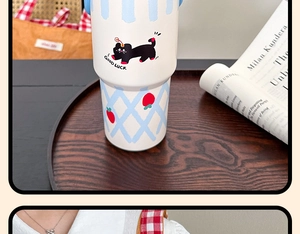 Detail of white tumbler with cat and strawberry pattern on a wooden tray setting