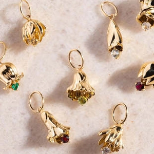 Macro view of flower-shaped golden pendants with multicolored gemstones on stone surface
