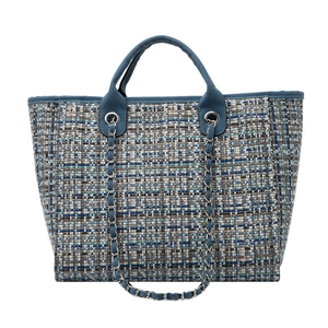 Detail view of large tweed bucket bag with blue contrast weave and metal chain strap