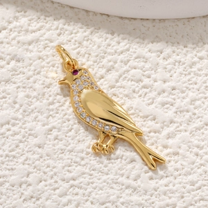Gros plan du pendentif oiseau doré avec cristaux et détail de gemme rose magenta