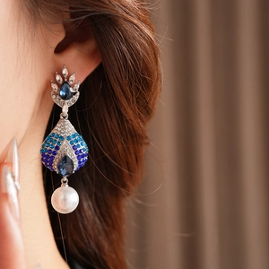 Dettaglio di orecchini vintage con zaffiro blu, strass e pendente di perle