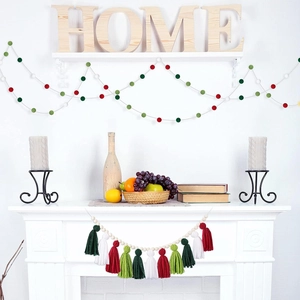 Close-up of festive wall hanging with wood beads, red green white felt balls and tassels