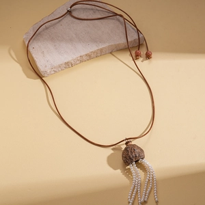 Sautoir ethnique avec pendentif en noix et glands de perles sur un fond en pierre