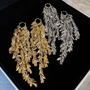 Macro shot of gold and silver leaf tassel earrings inside a black velvet jewelry box