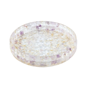 Transparent resin jewelry dish with amethyst stones and gold foil flakes on white backdrop
