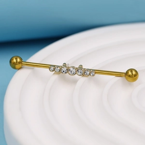 Vue détaillée d'un piercing industriel doré orné de six zircons ronds clairs au centre