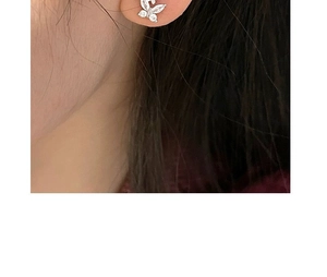Macro shot of silver butterfly stud earrings with zircon crystals worn on the ear