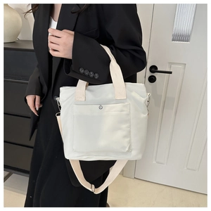 Detalle del bolso tote de nailon blanco con botón de presión plateado y correas tejidas