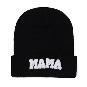 Detailed view of the MAMA embroidered patch on the cuff of a black knitted beanie cap