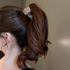 Detail of a Y2K star-shaped hair claw clip with pink rhinestones on a high ponytail