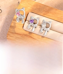 Macro detail of cat-shaped titanium steel ear studs with heart-shaped cubic zirconia stones
