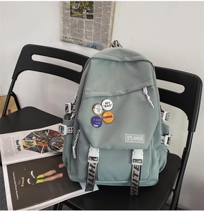Detail of light green canvas backpack with fun badges and stylish printed straps on a chair