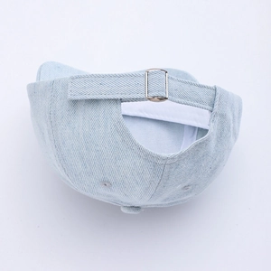 Detail of light blue denim baby cap featuring adjustable silver metal buckle and neat stitching