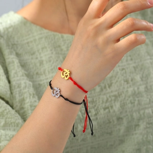 Detail of red and black woven yoga bracelets with gold and silver Om symbol charms