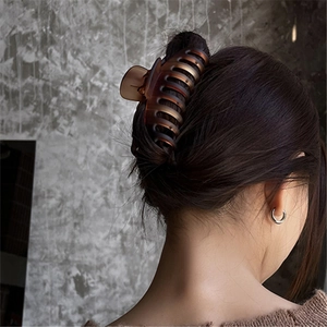 Large amber matte shark hair claw clip shown on long brown hair with multi-tooth grip
