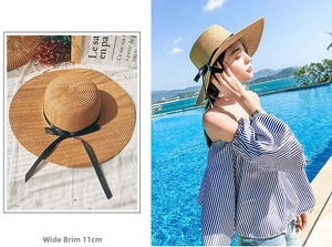 Detail view of 11cm wide brim straw hat with elegant black ribbon bow for sun protection