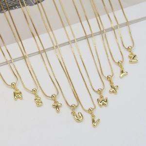 Detail of 18k gold plated bubble letter pendants R to Z on delicate chains in a layout