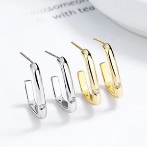 Dettaglio di orecchini a cerchio a U color oro e argento con piccoli accenti di cristallo