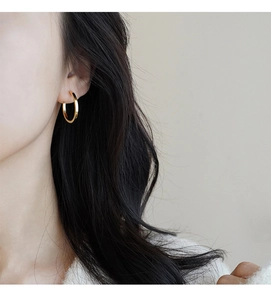 Close-up of elegant gold hoop earrings worn by a model with long dark hair