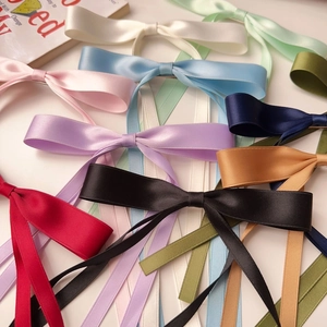 Flat lay showcasing colorful silk satin bow hair clips with long elegant ribbons