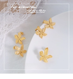 Macro shot of 18k gold plated surgical titanium steel floral earrings with brushed texture