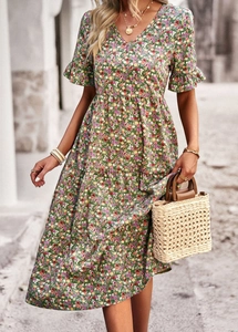 Detail of green V-neck floral dress with ruffle sleeves and tiered skirt in sunlight