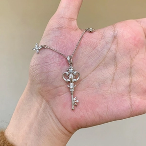 Detailed view of an intricate silver key pendant with zircon accents and a star charm