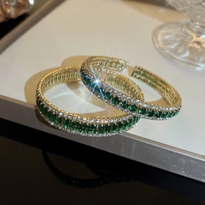 Macro shot of gold emerald bangle with rectangular stones and pavé diamond detailing
