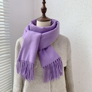 Close-up of purple cashmere-like scarf with fringe tassels worn by a model in soft light