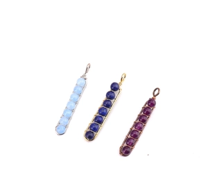 Detail of handmade wire wrapped U-shaped pendants with colorful crystal beads in three colors