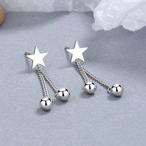 Macro shot of 925 sterling silver star stud earrings with long chain tassels and ball drops