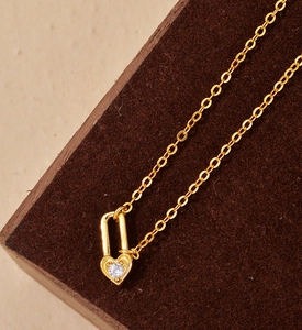 Detailed macro view of heart lock pendant with sparkling white zircon in gold finish